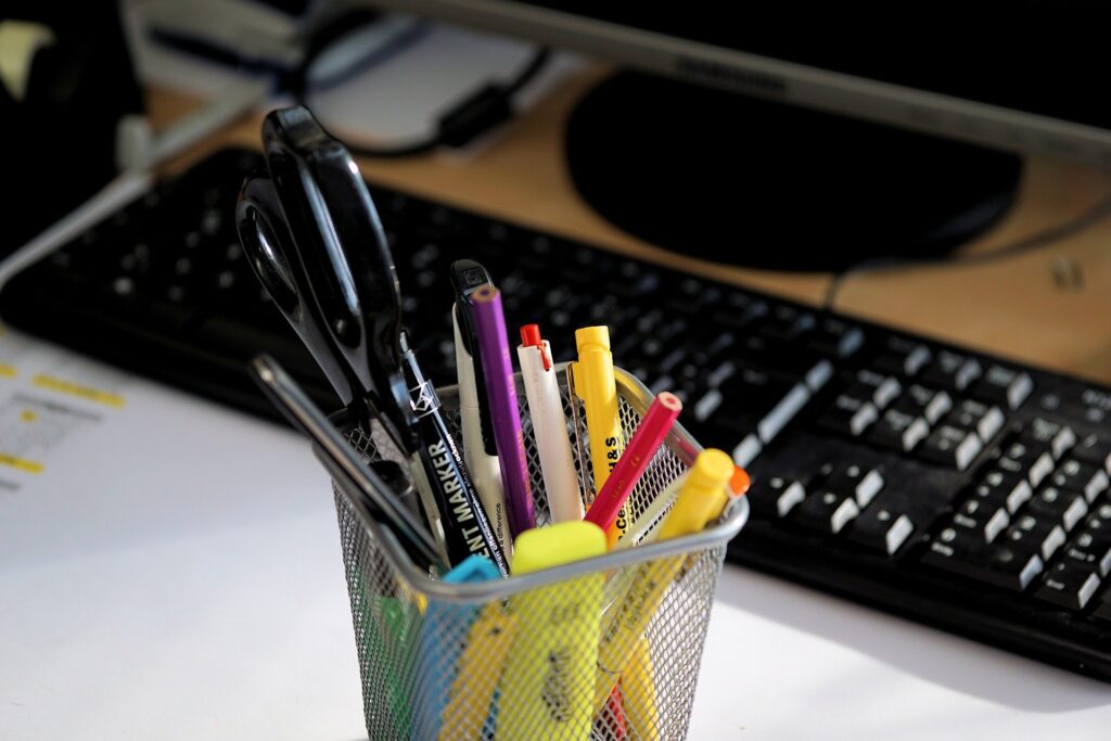 container with office tools in it beside keyboard