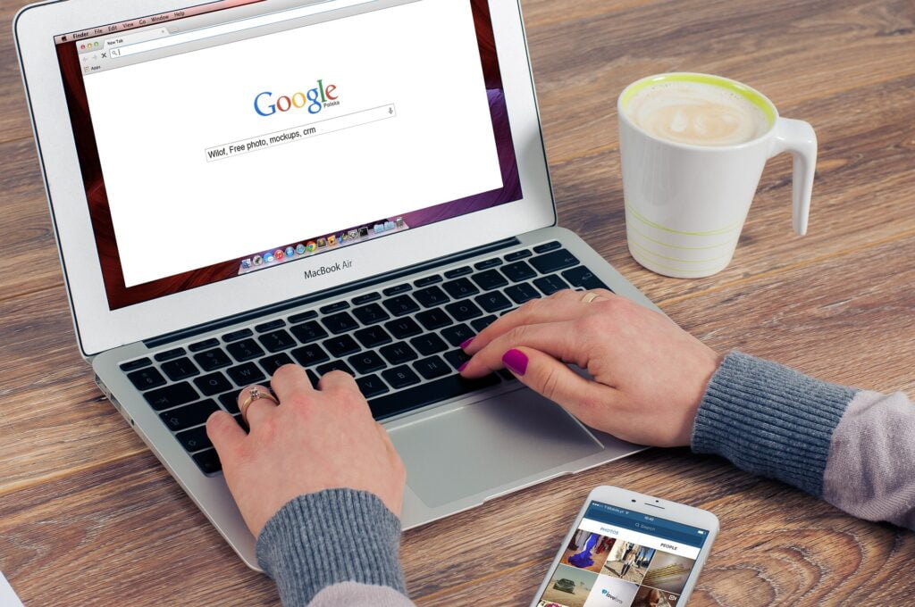 woman's hands typing on laptop that shows Google homepage