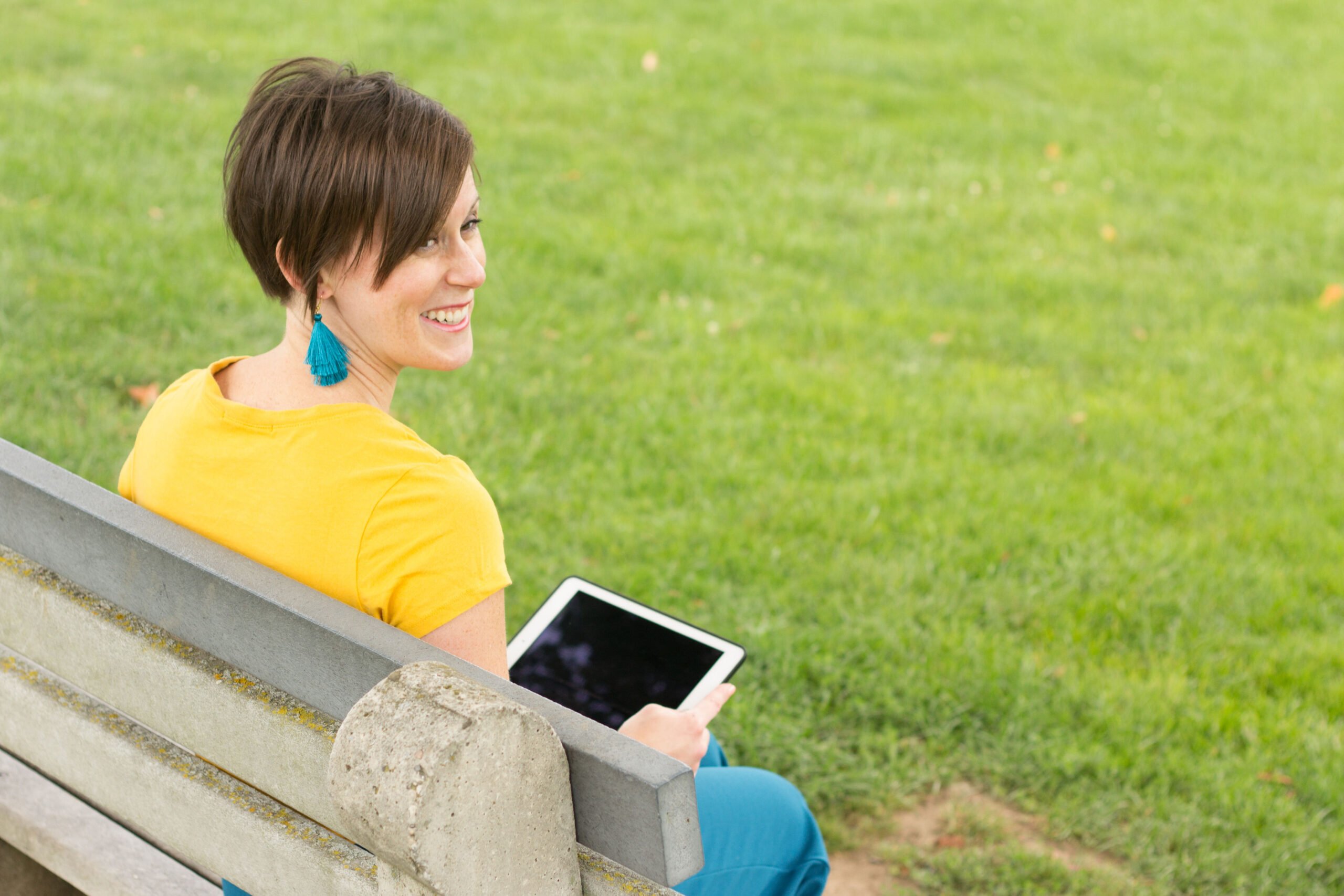 woman sitting on bench holding ipad