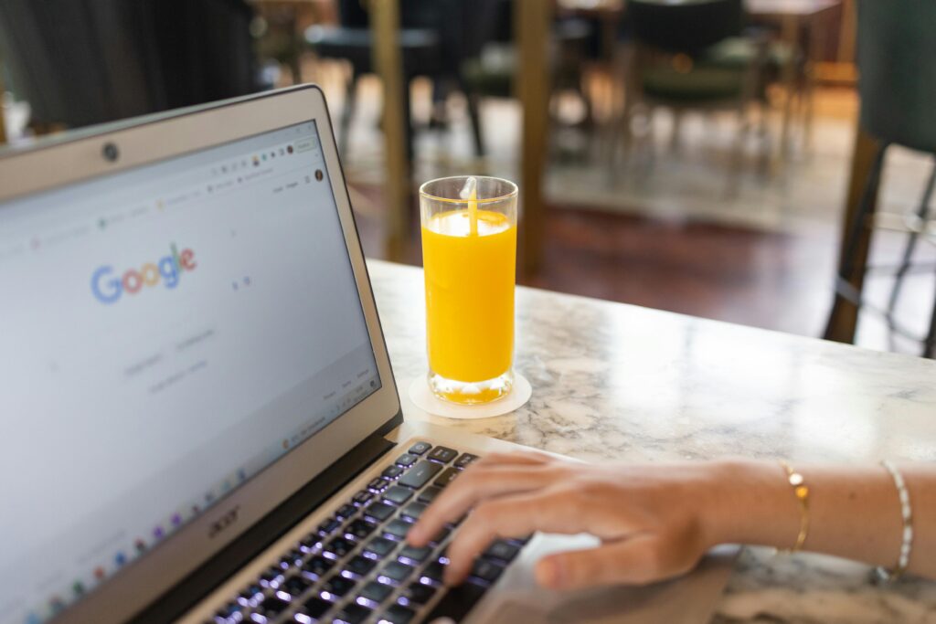 image of Google home screen on laptop next to a glass of orange juice