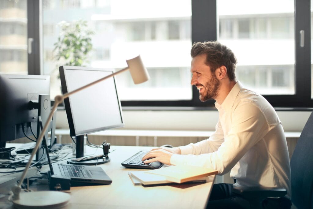 man smiling while reading computer screen