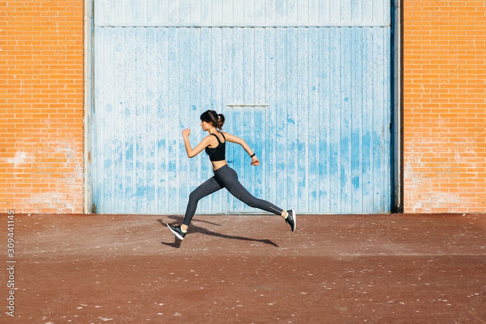 Young runner passing in front of a big blue metal door