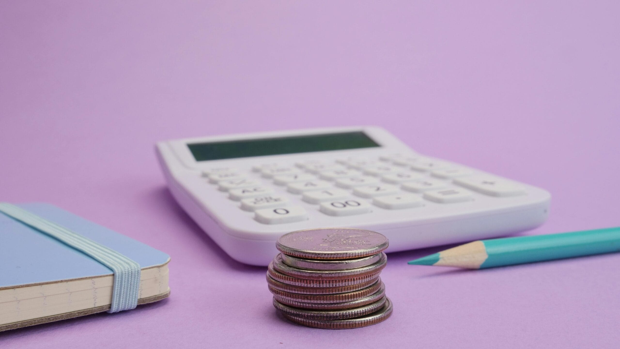 calculator, teal pencil crayon, and stack of coins