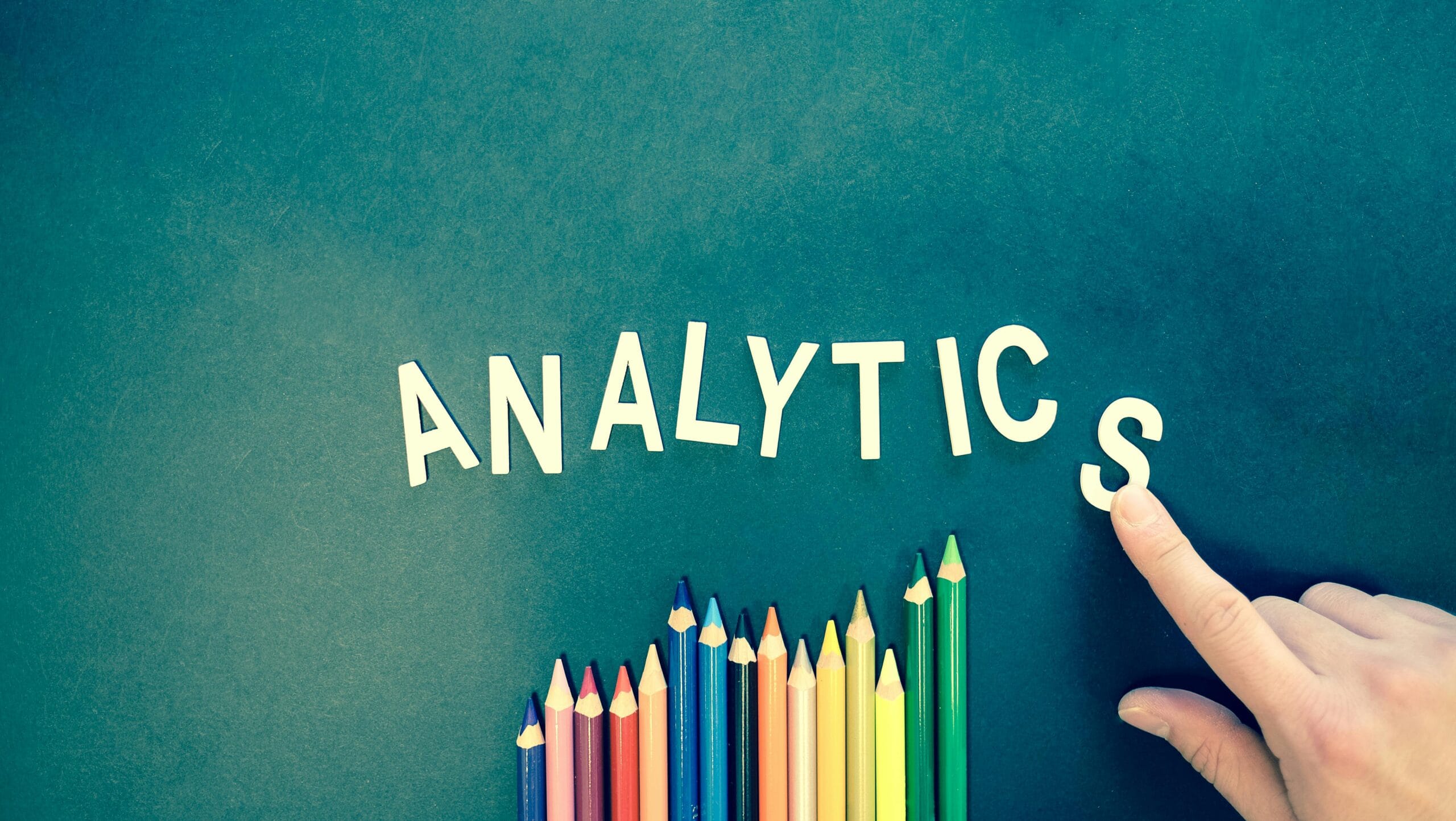 the word 'analytics' over a bunch of rainbow-coloured pencil crayons