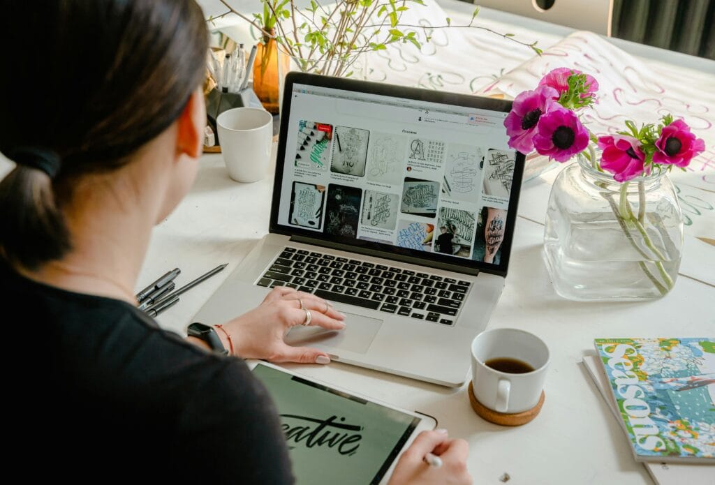 woman sitting at table looking at images on laptop