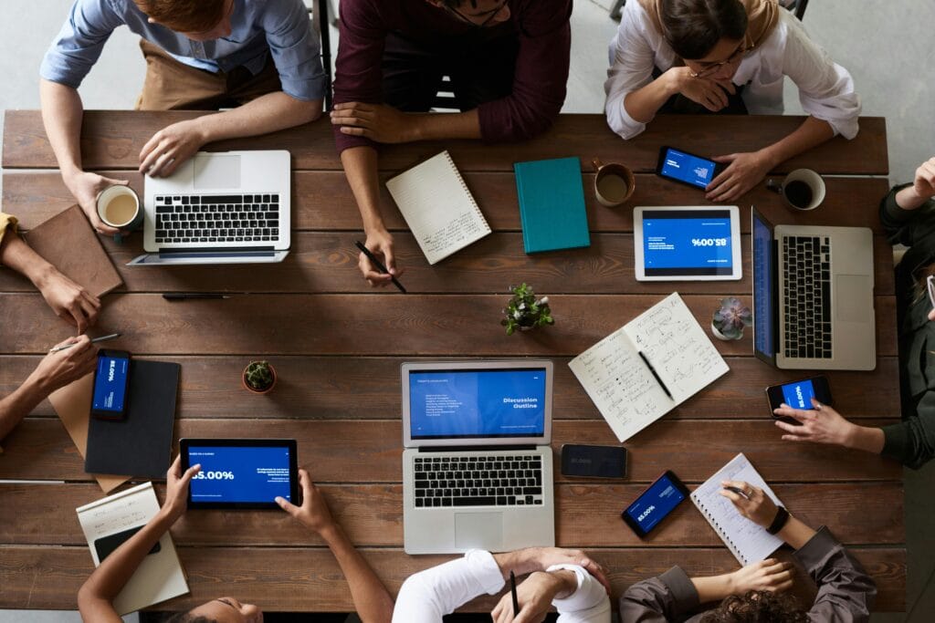 a group of people at an office table reviewing information on their laptops