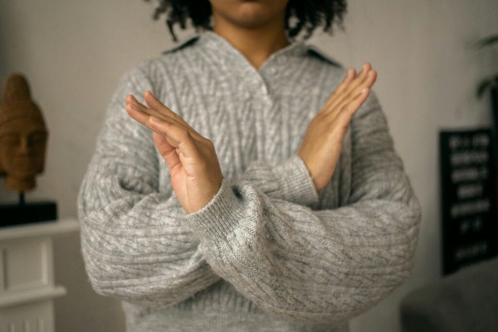 woman in grey sweater with arms crossed infront of her for the 'no' symbol